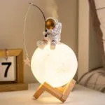 Lampe de nuit lune avec figurine d'astronaute et poisson rouge en verre.