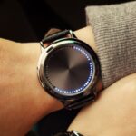 Montre connectée moderne avec écran circulaire lumineux et design élégant, portée au poignet d'une personne. Parfaite pour la technologie et la décoration scientifique.