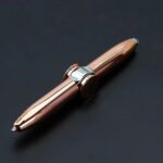 Stylo en métal rose doré avec clip argenté, élégant et moderne, posé sur un fond noir. Parfait pour une décoration scientifique ou un accessoire de bureau sophistiqué.