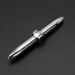 Stylo en métal chromé brillant, élégant et moderne, posé sur un fond noir, idéal pour la décoration scientifique ou de bureau.