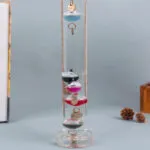 Boule à neige scientifique contenant des anneaux métalliques suspendus dans un liquide clair, utilisée comme décoration éducative ou de bureau.