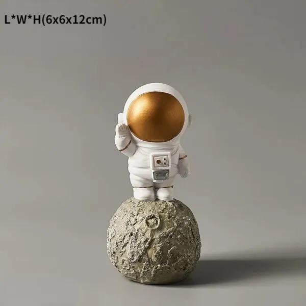 Figurine d'astronaute en plastique blanc avec casque doré brillant, posée sur une petite lune en pierre.