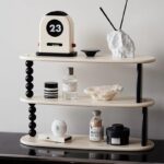 Décoration intérieure avec un calendrier vintage, objets minéraux et accessoires modernes sur une étagère design, créant une ambiance sophistiquée et contemporaine.
