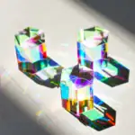 Trois cristaux en verre colorés avec reflets irisés, projetant des ombres colorées sur une surface sombre.