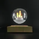 Lampe décorative en verre avec pulsations lumineuses jaunes et orange, posée sur une base en bois, création moderne pour décoration scientifique ou design intérieur.