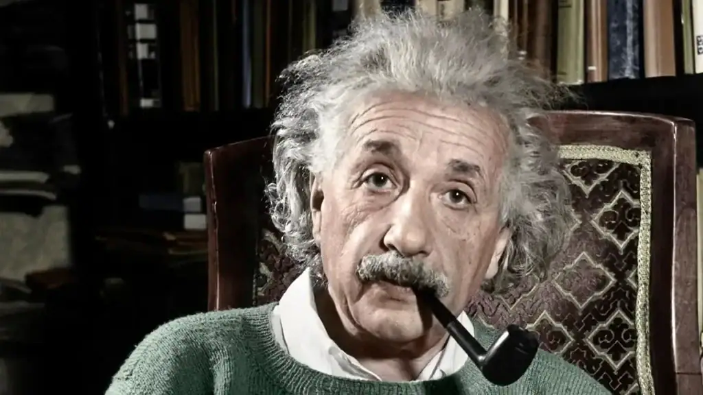 An image of Albert Einstein sitting in a study, holding a pipe in his mouth, surrounded by books and scientific memorabilia, showcasing his iconic appearance and intellectual environment.