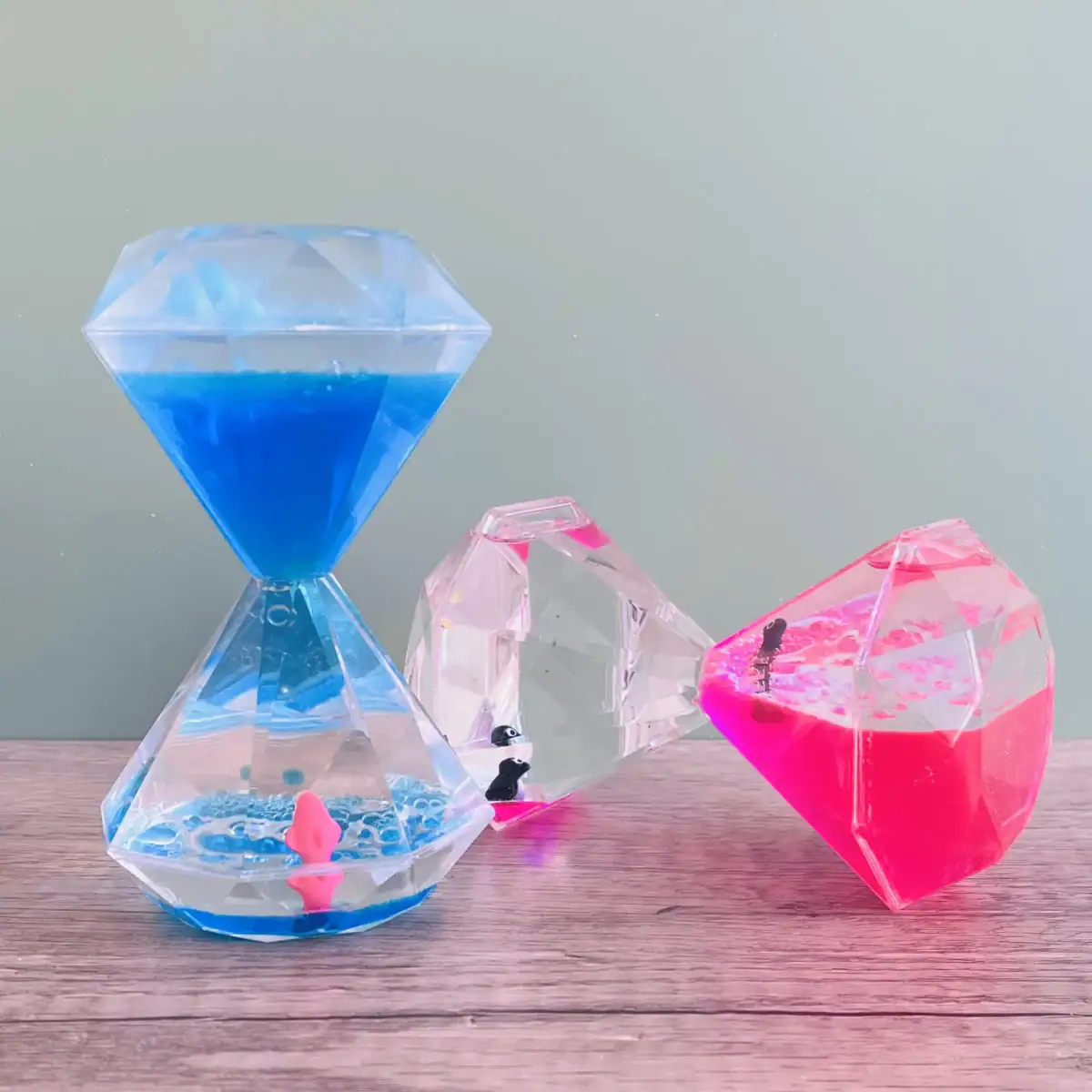 Sablier décoratif avec liquides bleus, roses et transparents, en forme de cristaux, idéal pour la décoration scientifique ou moderne.
