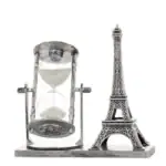 Sablier avec la Tour Eiffel miniature, symbole de la science et du voyage dans le temps, sur une base en bois.