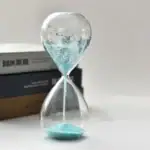 Sablier scientifique en verre avec sable bleu, symbole de la mesure du temps, idéal pour la décoration de bureau ou d'études scientifiques.