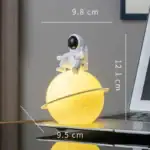 Lampe de décoration en forme de planète avec astronaute, lumière douce et design original pour une décoration scientifique.
