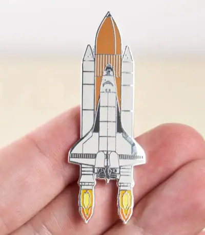 Pin's en forme de vaisseau spatial avec détails en métal, illustrant une fusée prête à décoller, parfait pour les amateurs d'astronomie et de science.