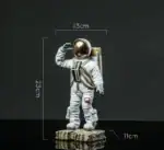Figurine d'astronaute miniature avec casque doré, mesurant 23,5 cm de haut, 13 cm de large et 11 cm de profondeur, idéale pour la décoration scientifique ou de collection.