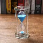 Sablier en verre avec sable bleu, symbole de la mesure du temps, idéal pour la décoration scientifique ou éducative.