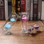 Horloges de sable en verre avec poudres colorées roses, bleues et violettes, utilisées comme décoration scientifique ou pour la mesure du temps.