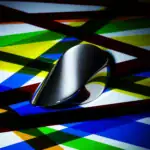 Pointeur de souris noir brillant placé sur un fond coloré abstrait avec des lignes diagonales multicolores.