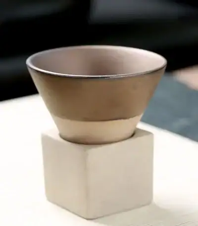 Petit pot en céramique beige posé sur un socle en béton blanc, idéal pour la décoration scientifique ou de bureau.