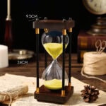 Sablier décoratif en bois et verre, mesure 24 cm de haut et 9,5 cm de large, parfait pour la décoration de bureau ou intérieur.