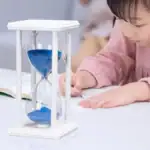 Horloge de sable avec cadre en bois blanc et sable bleu, utilisée comme objet éducatif ou décoration scientifique.