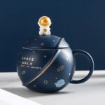 Vase en forme de planÚte avec un petit astronaute doré sur le couvercle, décoré d'étoiles et de planÚtes, parfait pour une décoration scientifique ou spatiale.