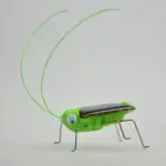 Objet scientifique lumineux en forme de grillon vert avec antennes lumineuses et pattes métalliques.