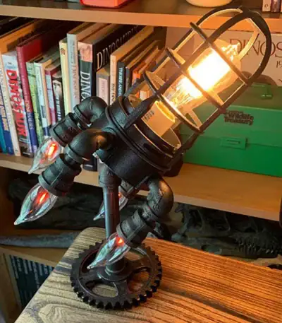 Lampe de bureau design inspirée d'une fusée avec éclairage chaud et structure métallique noire. Parfaite pour une décoration moderne ou thématique scientifique.