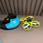 Mini drone avec quatre hélices colorées et casque de protection, idéal pour apprendre à piloter en toute sécurité. Parfait pour les amateurs de technologie et de gadgets.