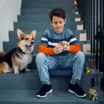 Jeune garçon avec un chien jouant avec un Rubik's Cube sur un escalier, ambiance décontractée et ludique.