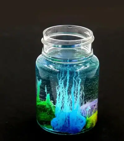 Vase en verre contenant une expérience scientifique avec des liquides colorés et des bulles, illustrant un phénomène chimique ou physique captivant.