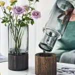 Vase en verre avec fleurs et support en bois, décoration de style moderne et naturel, parfait pour embellir votre intérieur avec une touche élégante et organique.