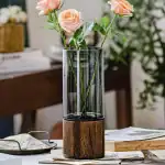 Fleurs roses dans un vase en verre avec socle en bois, décoration élégante et moderne pour intérieur.